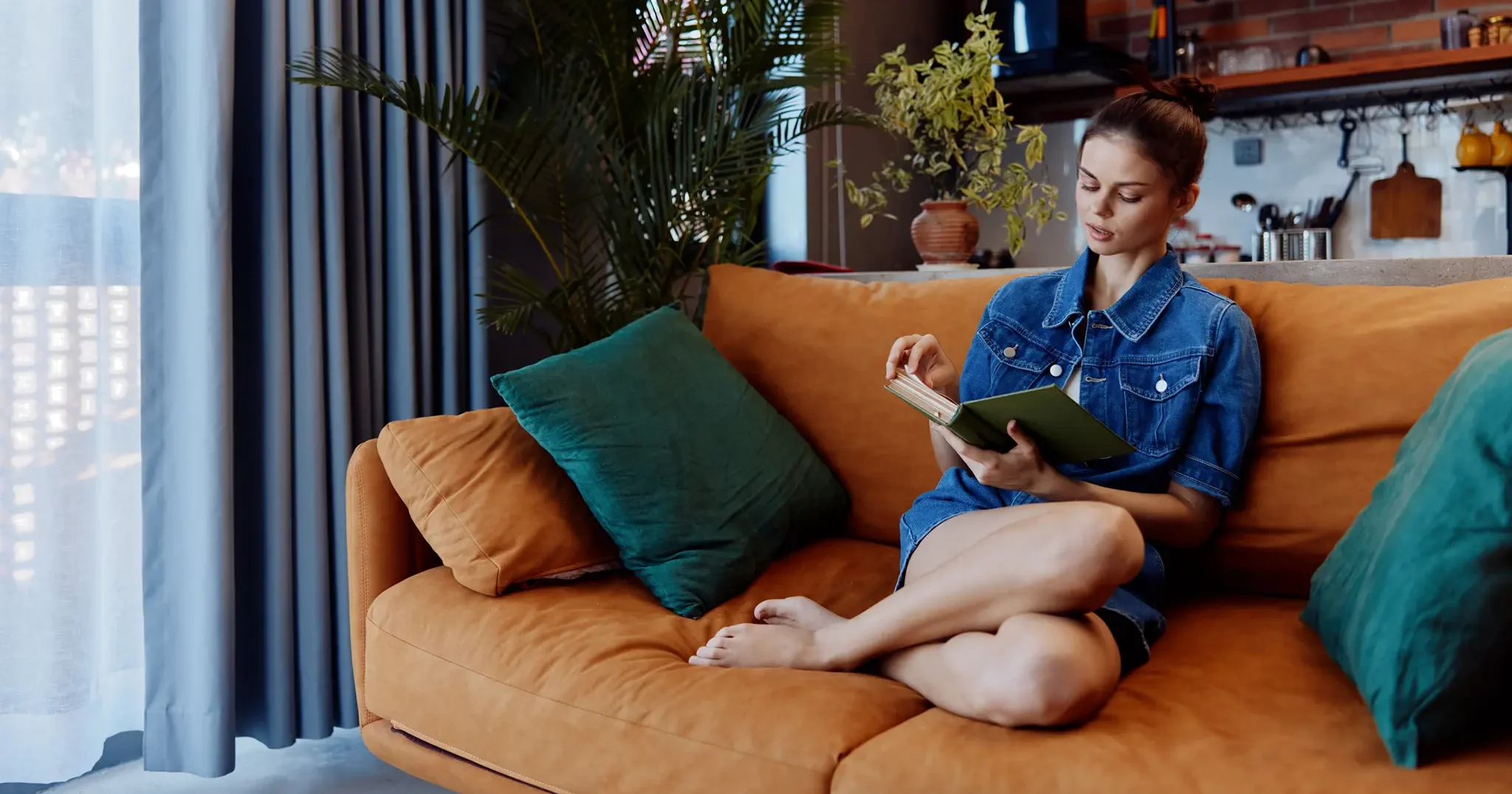 woman-relaxing-on-orange-couch-with-book-and-phone