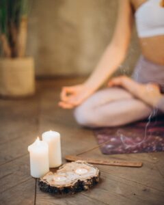A person meditating on a yoga mat with candles and incense in a peaceful setting.