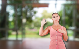 A woman in a pink dress with buttons stands outdoors, hand on chest, in a holistic approach to weight loss. The blurred green background suggests a serene setting, emphasizing a mindful, balanced method for wellness.